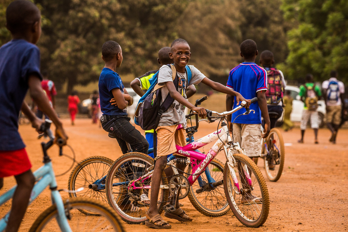 Kamsar, prefecture of Boké, Guinea. Children drive their bike across the youth centre. 